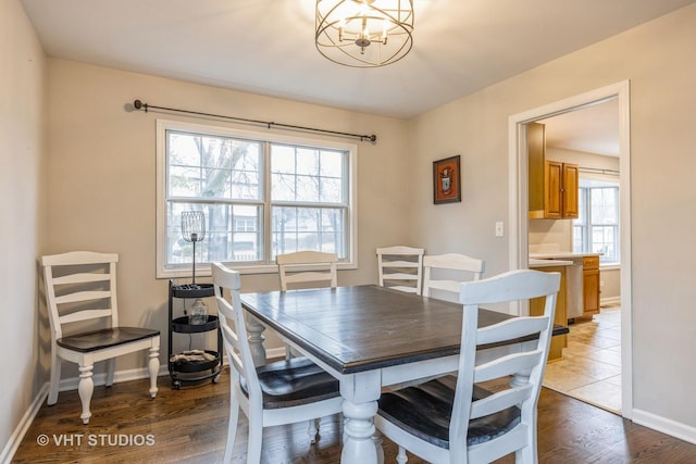 dining space featuring a chandelier, baseboards, and wood finished floors