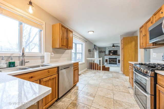 kitchen featuring a fireplace, stainless steel appliances, a sink, and light countertops