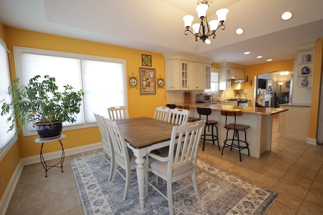 dining area featuring plenty of natural light, sink, an inviting chandelier, and a tray ceiling