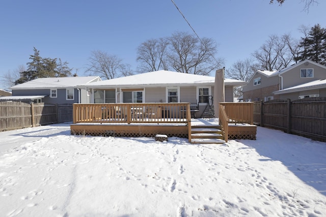 snow covered rear of property with a deck