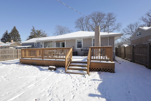 snow covered rear of property featuring a wooden deck