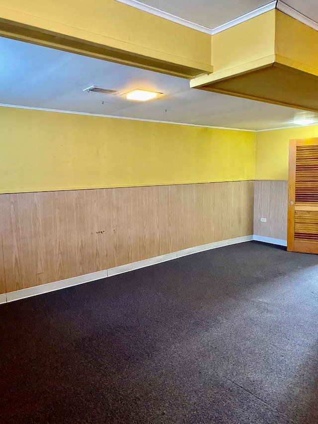 unfurnished room featuring carpet floors, wooden walls, and ornamental molding