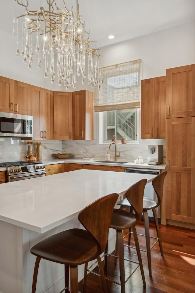 kitchen with a breakfast bar, sink, decorative light fixtures, dark hardwood / wood-style flooring, and stainless steel appliances