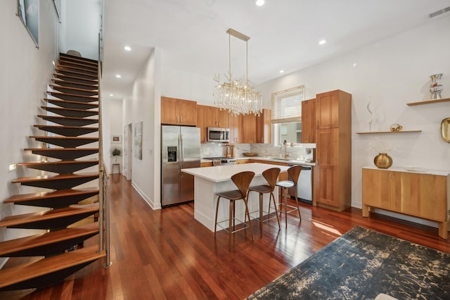 kitchen featuring decorative light fixtures, a kitchen breakfast bar, dark hardwood / wood-style flooring, a center island, and stainless steel appliances