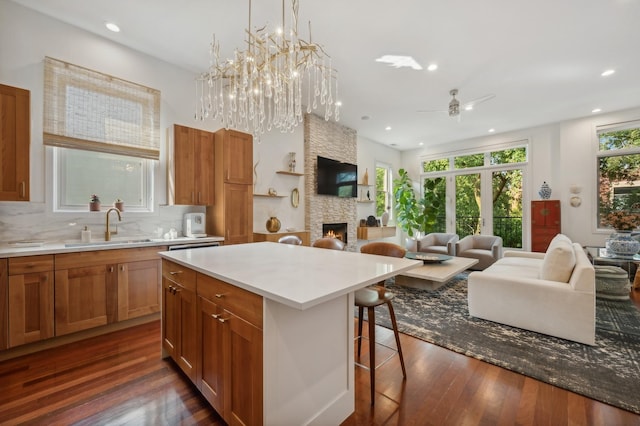 kitchen with sink, a kitchen breakfast bar, a kitchen island, a fireplace, and decorative backsplash