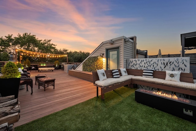 deck at dusk featuring an outdoor living space with a fire pit