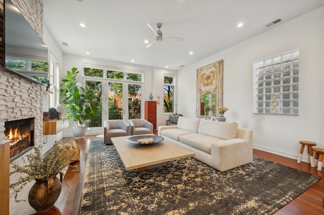 living room with a fireplace, wood-type flooring, and ceiling fan