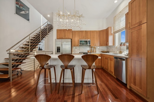 kitchen with sink, appliances with stainless steel finishes, a kitchen island, dark hardwood / wood-style flooring, and decorative light fixtures