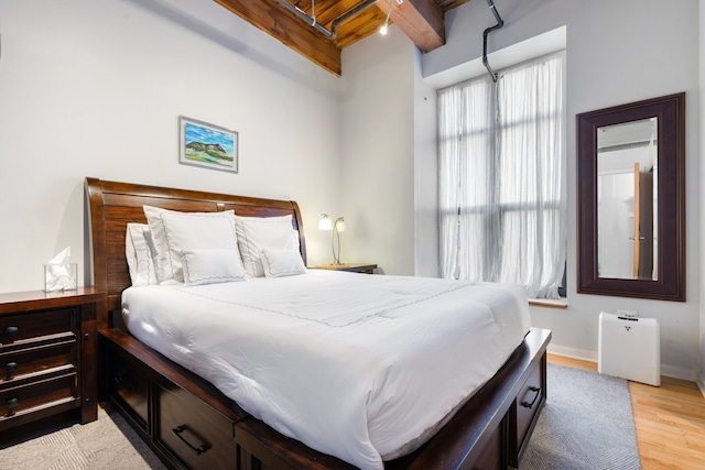 bedroom featuring beamed ceiling, wooden ceiling, and light wood-type flooring