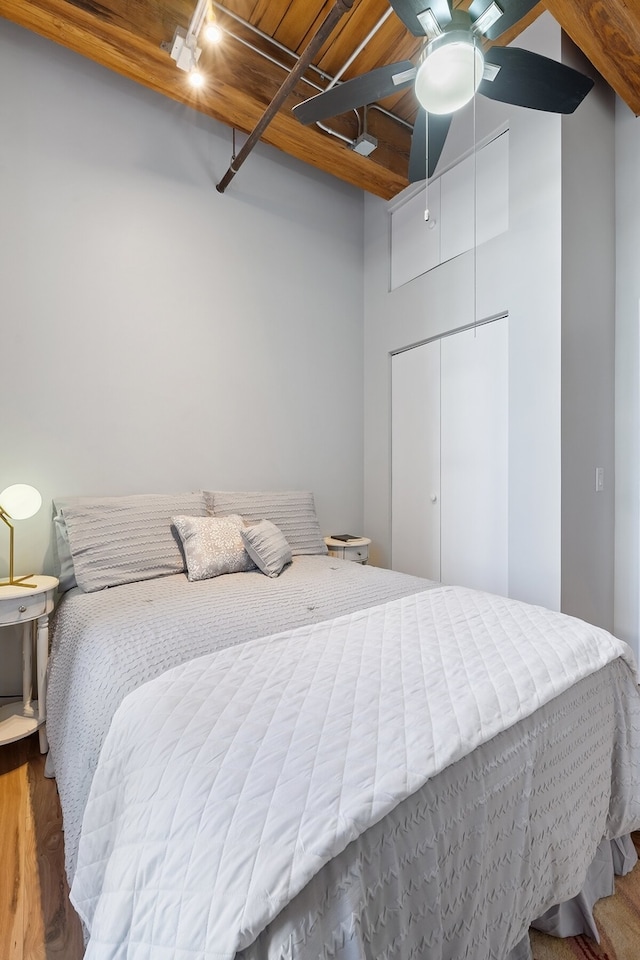 bedroom with rail lighting, ceiling fan, beam ceiling, wooden ceiling, and a closet