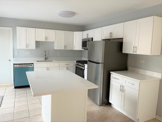 kitchen featuring light tile patterned flooring, appliances with stainless steel finishes, white cabinetry, sink, and a center island