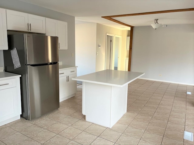 kitchen featuring white cabinetry, a kitchen island, light tile patterned floors, and stainless steel fridge