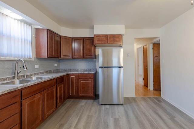 kitchen with sink, decorative backsplash, stainless steel fridge, and light wood-type flooring