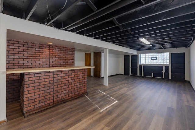 basement with dark wood-type flooring and brick wall