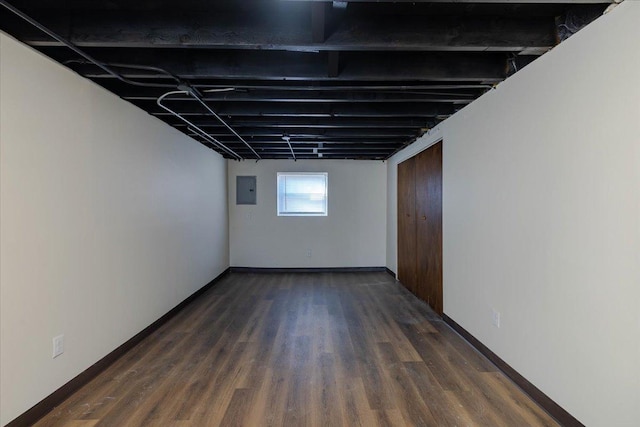 basement with dark wood-type flooring and electric panel