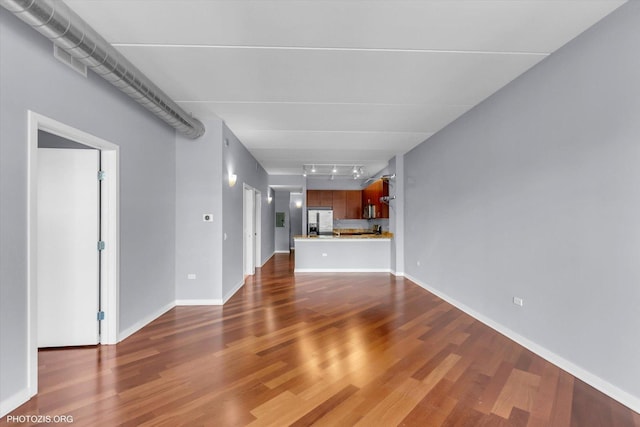 unfurnished living room with dark wood-type flooring and track lighting