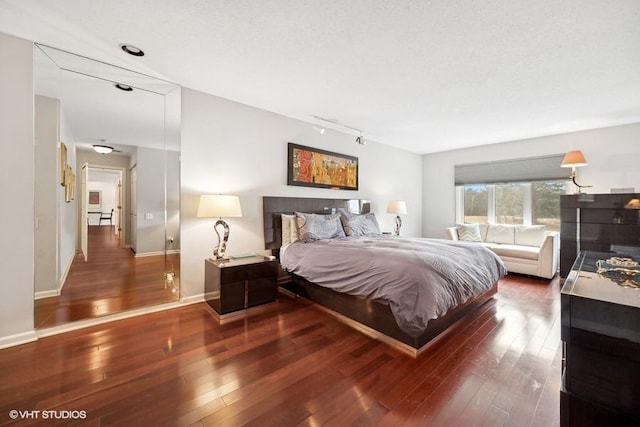 bedroom featuring track lighting and dark hardwood / wood-style floors