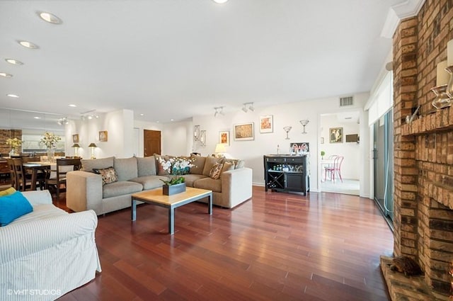 living room with dark hardwood / wood-style flooring and a brick fireplace