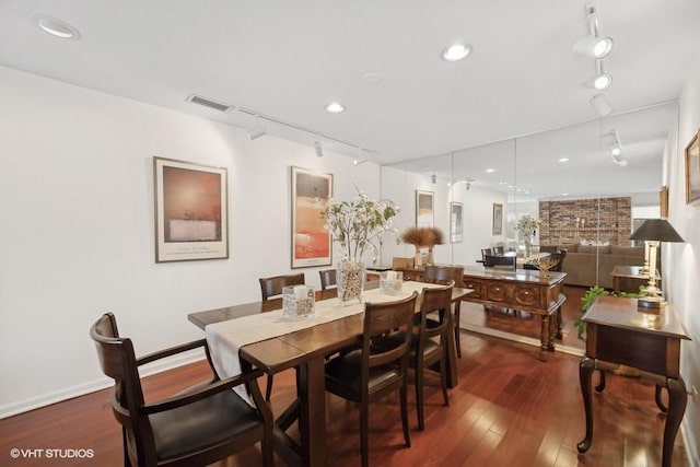 dining room with dark hardwood / wood-style floors and rail lighting