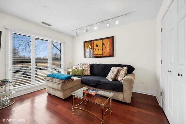 living room featuring track lighting, dark hardwood / wood-style floors, and a textured ceiling