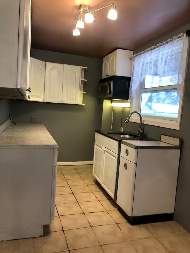 kitchen featuring sink, light tile patterned floors, and white cabinets