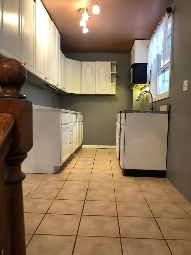 kitchen featuring light tile patterned floors, sink, and white cabinets