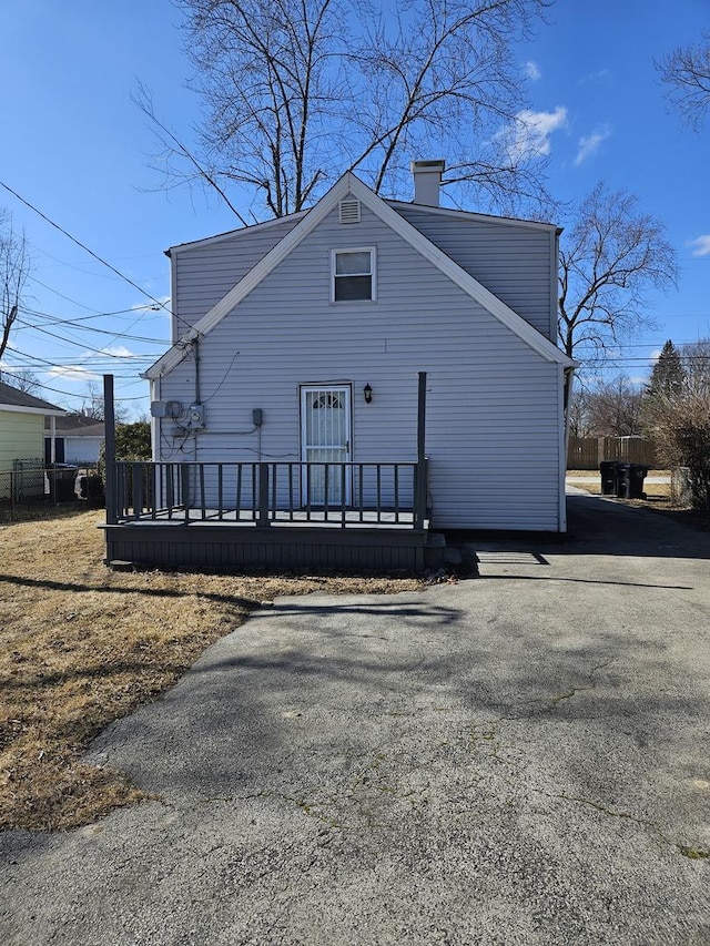 exterior space featuring a deck, aphalt driveway, and a chimney