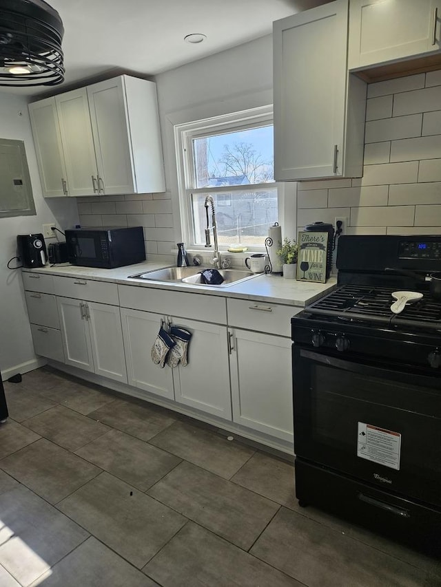 kitchen with a sink, white cabinetry, light countertops, electric panel, and black appliances