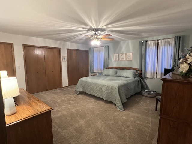 bedroom with two closets, ceiling fan, and carpet flooring