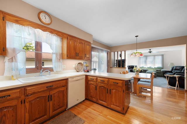 kitchen with pendant lighting, sink, white dishwasher, kitchen peninsula, and light wood-type flooring