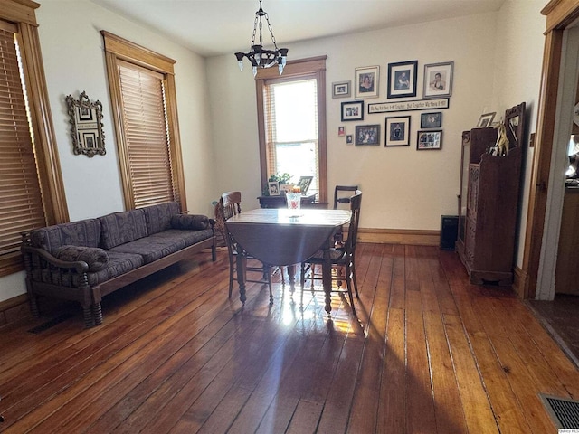 dining room with dark wood-type flooring and a chandelier