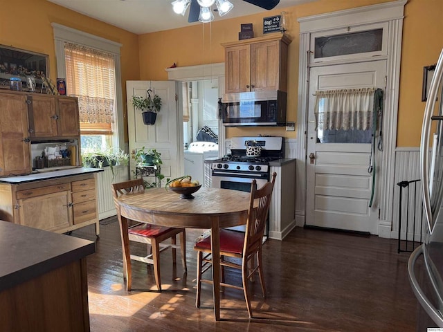 kitchen with stainless steel appliances, washer / dryer, dark wood-type flooring, and ceiling fan