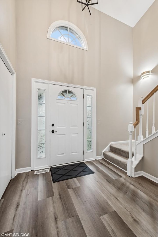 foyer featuring a towering ceiling and wood-type flooring