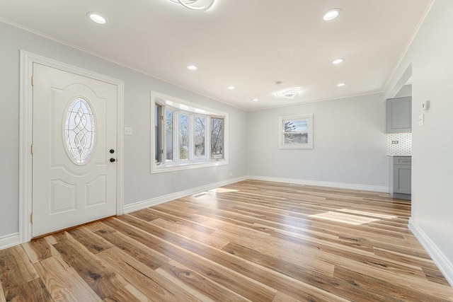 entrance foyer featuring ornamental molding, a wealth of natural light, and light wood-type flooring