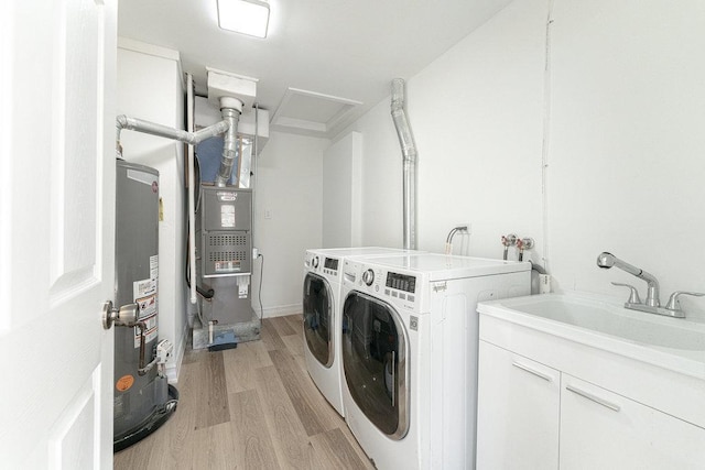 laundry room with washer and dryer, sink, light hardwood / wood-style flooring, water heater, and heating unit