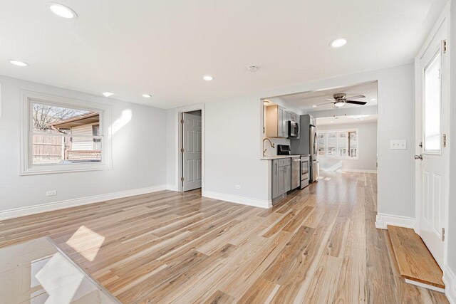 unfurnished living room with ornamental molding, a large fireplace, ceiling fan, and light hardwood / wood-style flooring