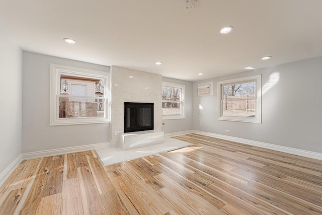 unfurnished living room featuring a premium fireplace and light hardwood / wood-style flooring