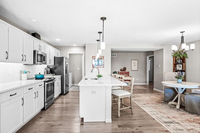 kitchen featuring stainless steel appliances, sink, a kitchen island with sink, and pendant lighting