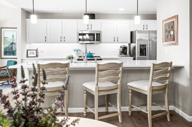 kitchen featuring stainless steel appliances, decorative light fixtures, and white cabinets