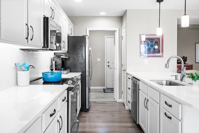 kitchen with white cabinetry, appliances with stainless steel finishes, sink, and decorative light fixtures