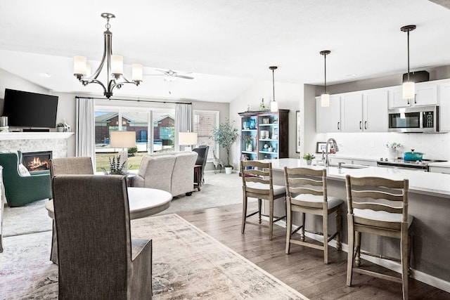 kitchen featuring sink, vaulted ceiling, pendant lighting, stainless steel appliances, and white cabinets