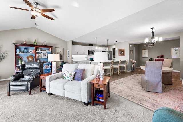 living room with ceiling fan with notable chandelier, vaulted ceiling, and carpet