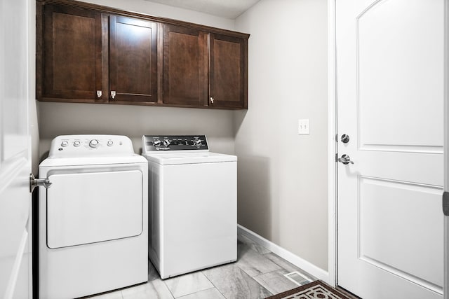 clothes washing area with cabinets and separate washer and dryer