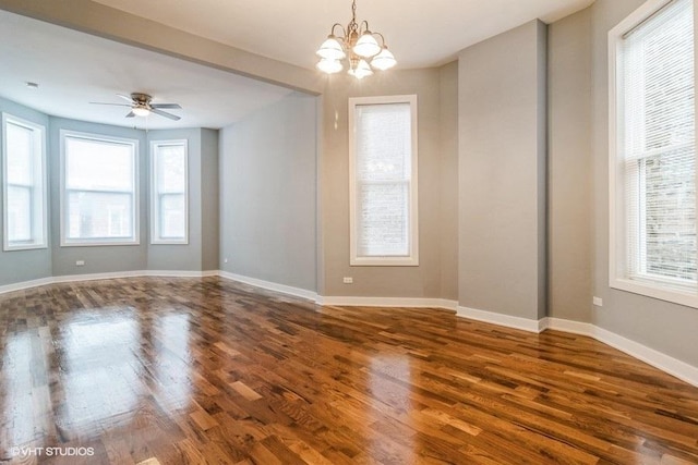 spare room with dark hardwood / wood-style flooring and ceiling fan with notable chandelier