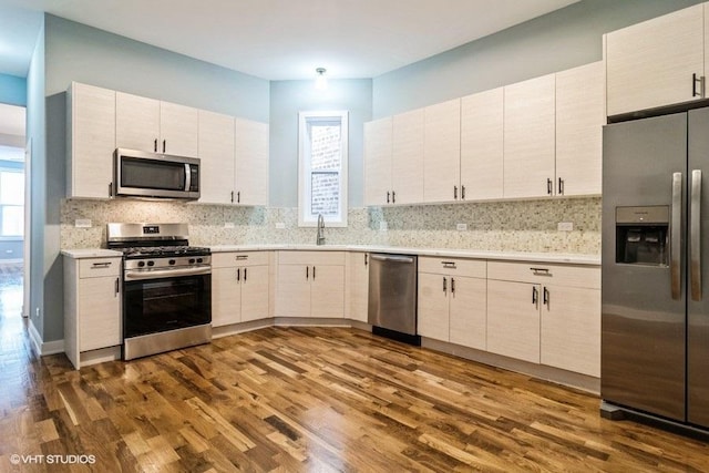 kitchen featuring dark wood-type flooring, white cabinets, appliances with stainless steel finishes, and backsplash