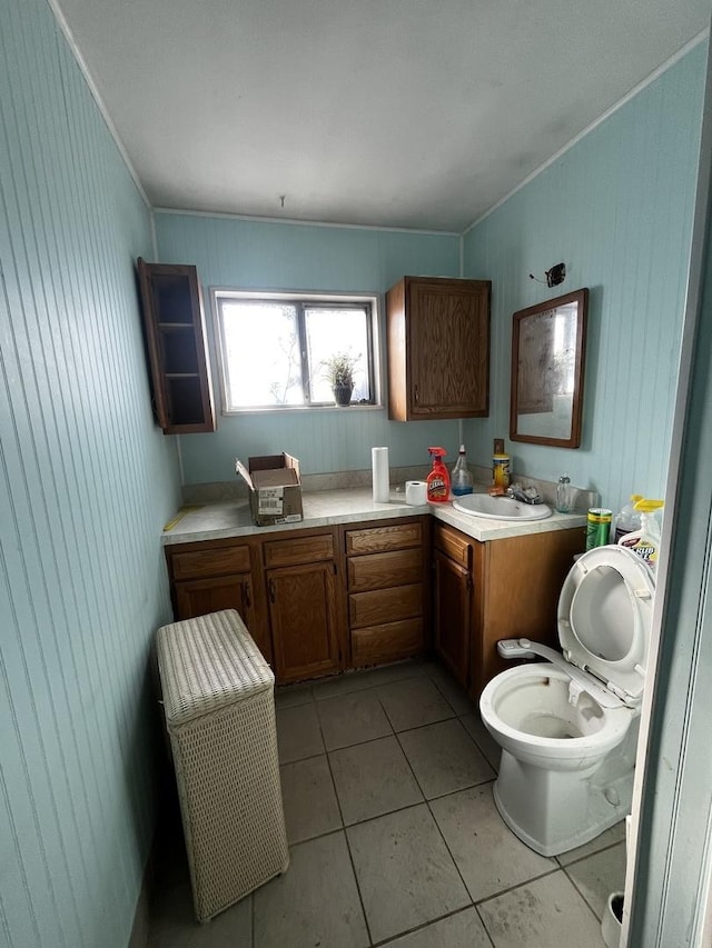 bathroom featuring tile patterned flooring, vanity, wood walls, and toilet