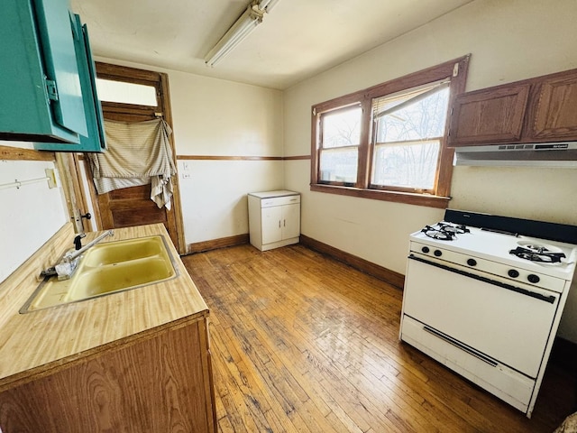 kitchen with sink, light hardwood / wood-style floors, gas range gas stove, and green cabinetry