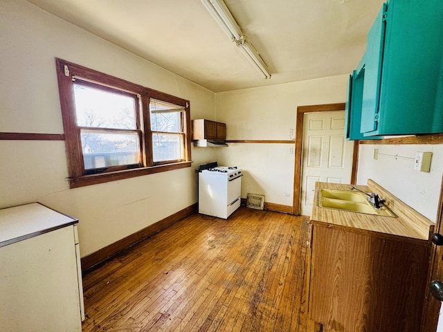 interior space with blue cabinetry, white range with gas cooktop, sink, and hardwood / wood-style floors