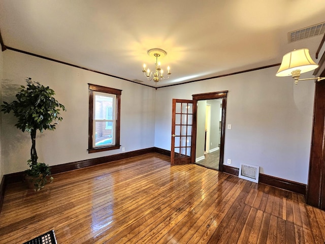 spare room featuring hardwood / wood-style floors, ornamental molding, and a chandelier