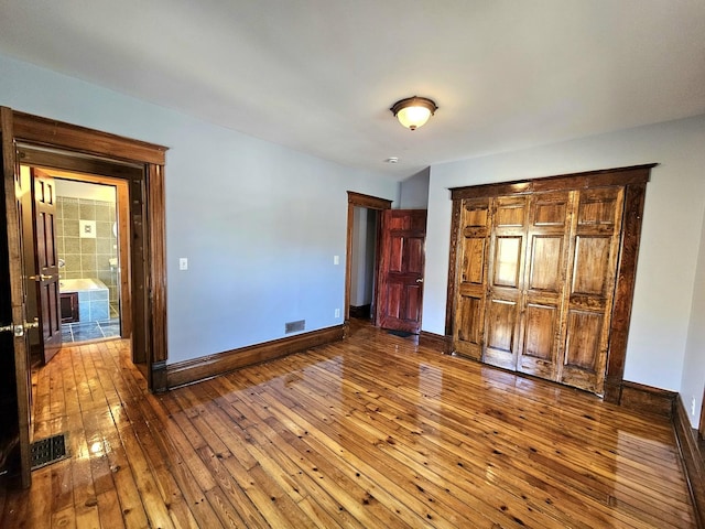 unfurnished bedroom with hardwood / wood-style flooring and ensuite bath